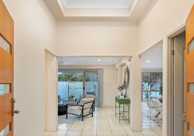 Bright entry hall with a skylight, opening to a living room and dining area with sliding doors to an outdoor patio.